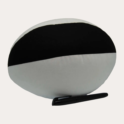 The reverse of the same plush ball, showing a wide black fabric band across the upper half against the white lower panels, with the black permanent marker laid flat in front.